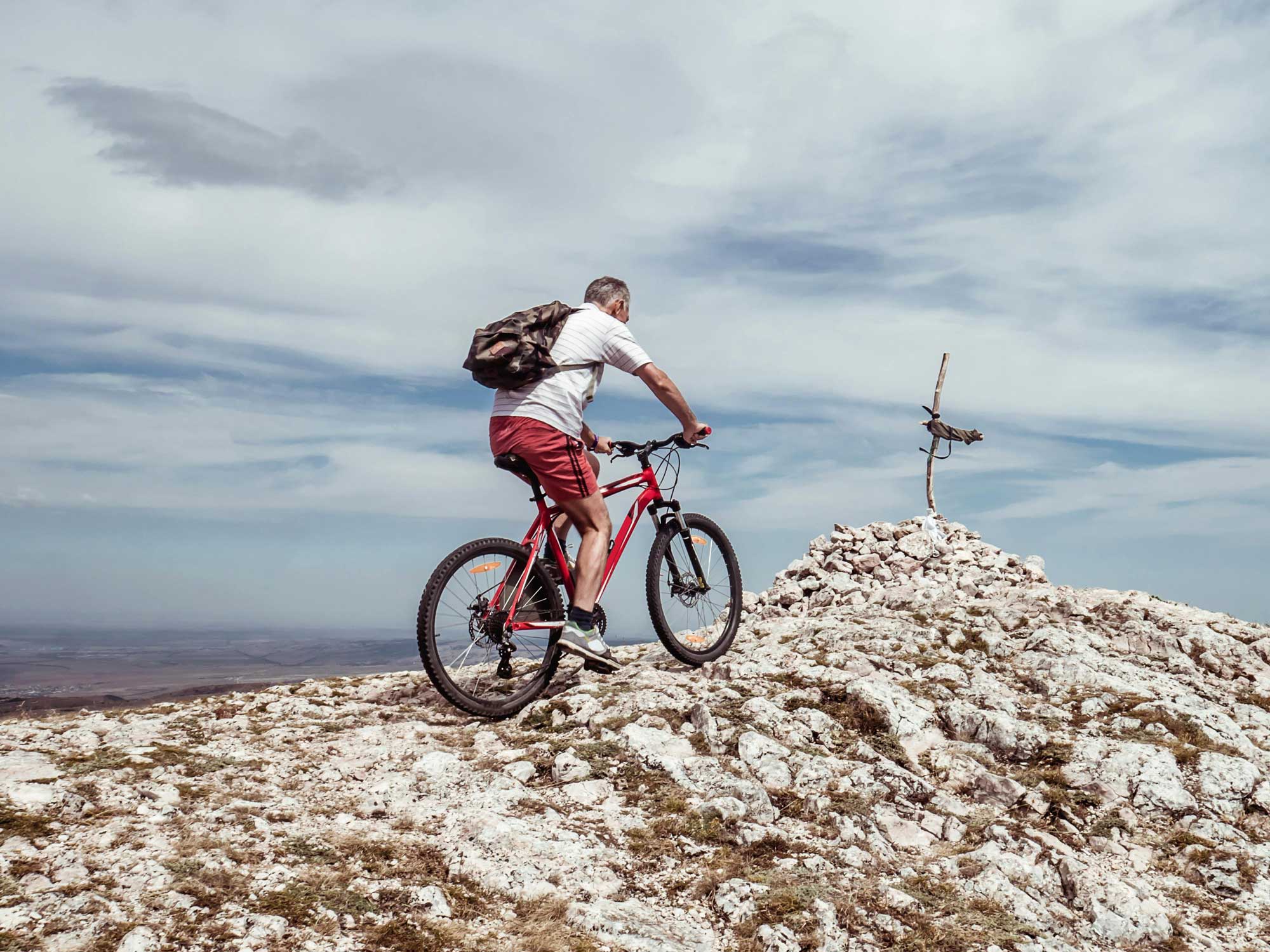 man biking to a ridge top of a mountain